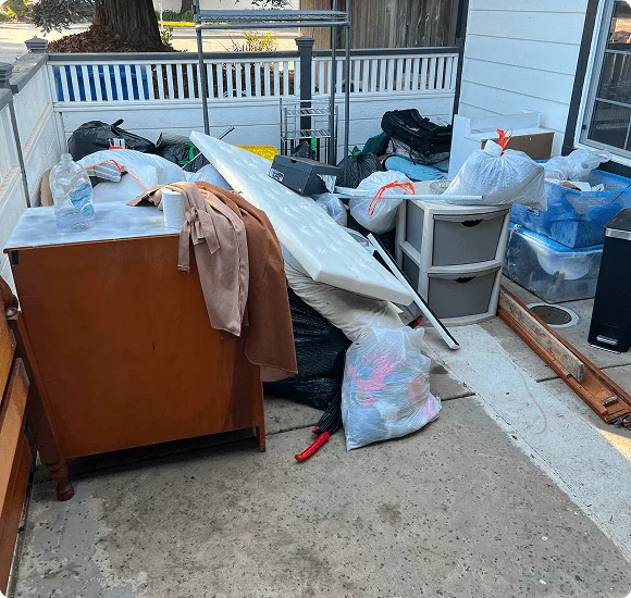 Dresser, bags and boxes set out on a porch for pickup